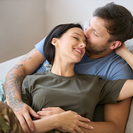 Image showing a young couple hugging each other on the sofa with the woman in army uniform