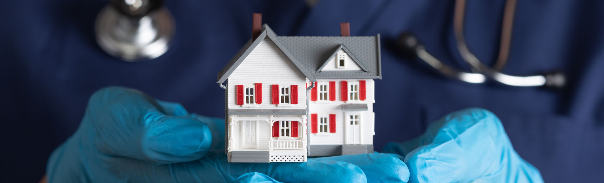 Image showing a close up of a doctor wearing gloves and holding a model house