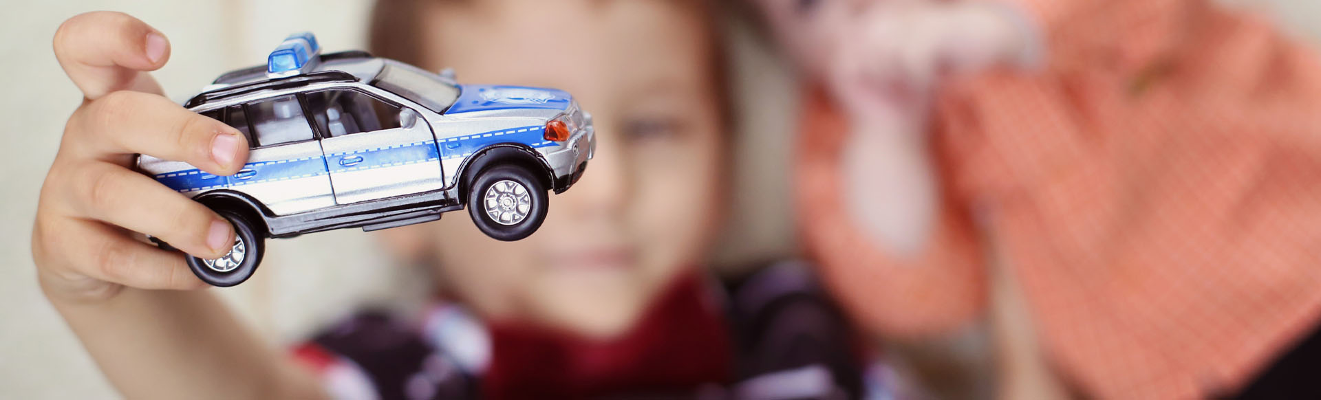 Image showing two small children kids looking at a toy police car that one of them is holding up