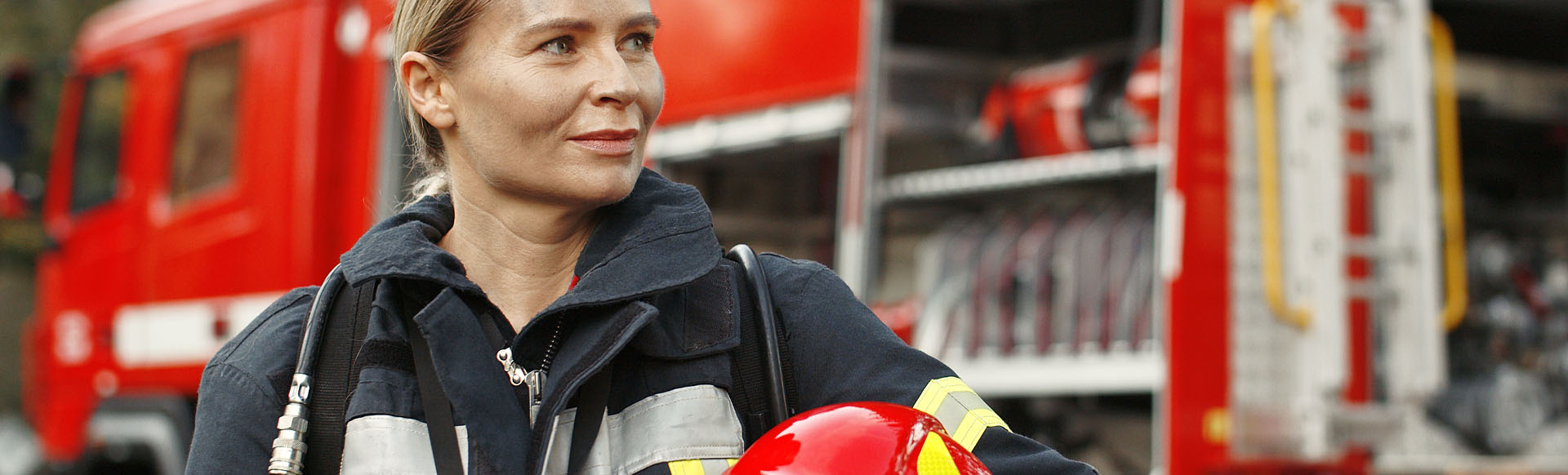 Image showing a firewoman holding her helmet in front of a fire truck