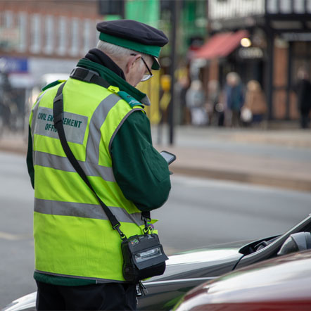 Image showing a civil enforcement officer applying a parking ticket to a car