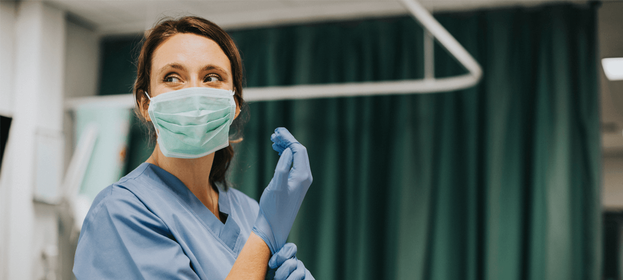 Female nurse with a mask putting on gloves