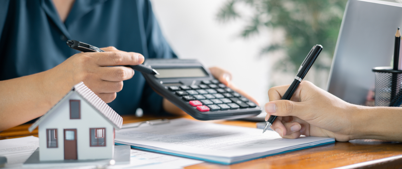 Image showing two people reviewing financial documents and a small model symbolize mortgage.