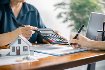 Image showing two people reviewing financial documents and a small model symbolize mortgage