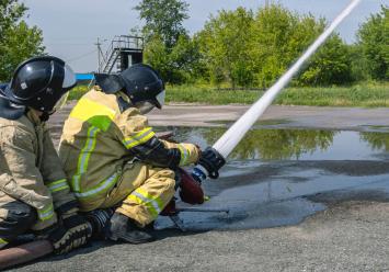 Firefighters in protective clothing extinguish the fire