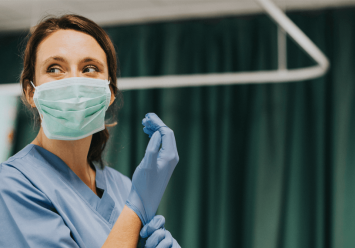 Female nurse with a mask putting on gloves