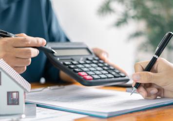 Image showing two people reviewing financial documents and a small model symbolize mortgage.