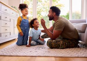 Image showing an army officer sat on the living room floor with his two children