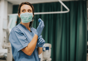 Female nurse with a mask putting on gloves