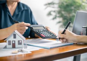 Image showing two people reviewing financial documents and a small model symbolize mortgage