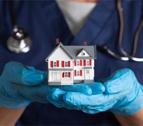 Image showing a close up of a doctor wearing gloves and holding a model house